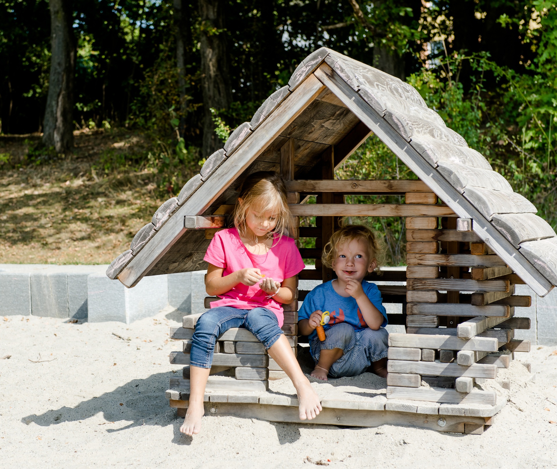 Children of different ages play in the forest playground