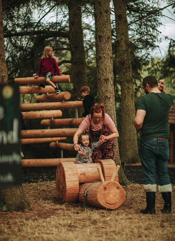 Kinder spielen mit ihren Eltern im Wald auf Richter Geräten