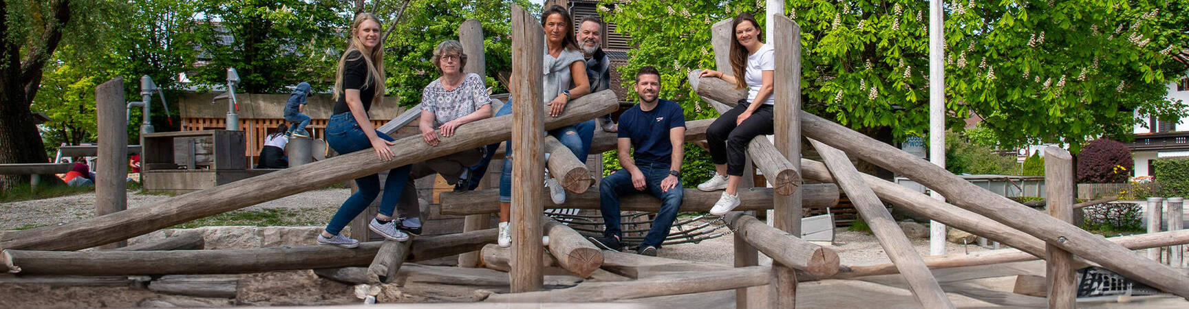 Sechs freundlich lächelnde Mitarbeiter aus dem Vertriebsteam auf einem Spielplatz