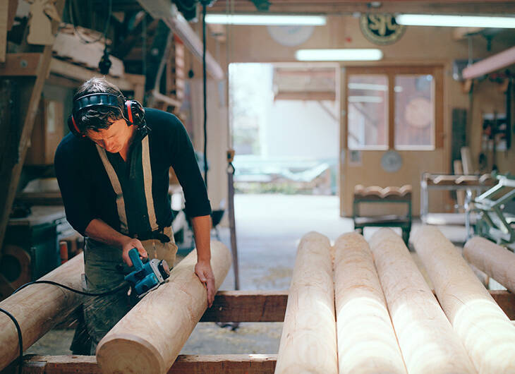 Werkstatt von Innen, in der ein Mitarbeiter gerade Holz schneidet